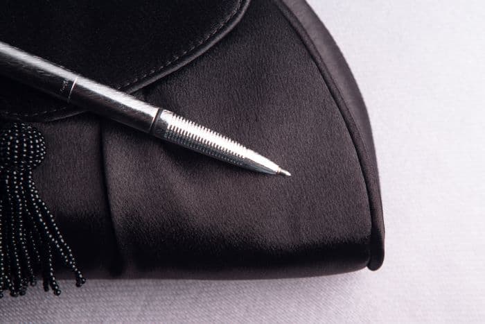 Open 400BRC brushed chrome bullet space pen laying atop a black clutch with a beaded tassel.
